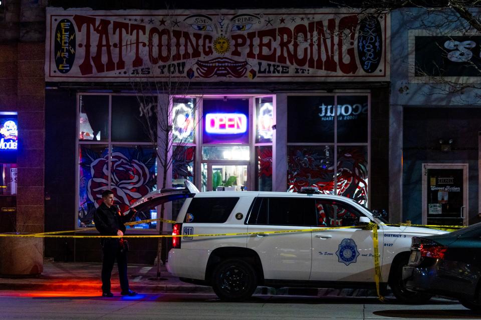 Police officers stand outside a tattoo shop in Denver where two women were killed and a man was injured in a shooting on December 27, 2021.