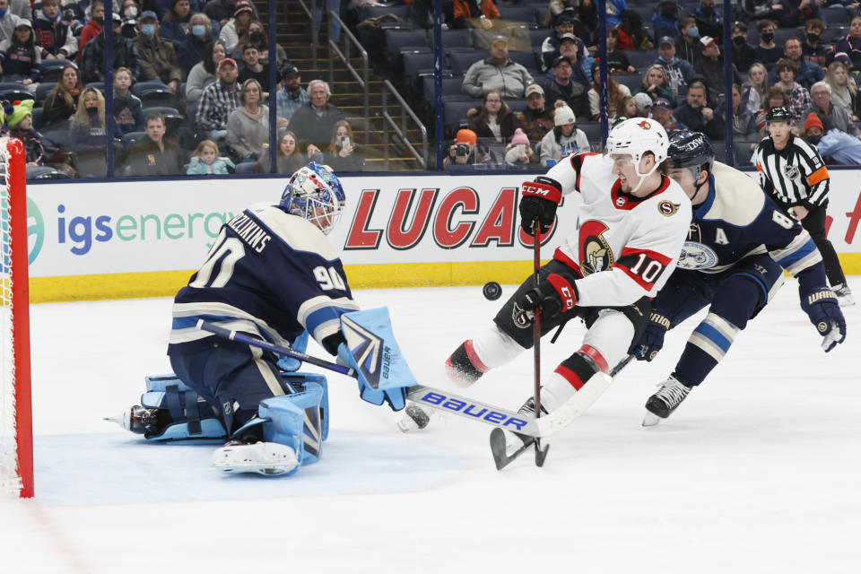 Columbus Blue Jackets' Elvis Merzlikins, left, makes a save against Ottawa Senators' Alex Formenton as Zach Werenski defends during the first period of an NHL hockey game, Sunday, Jan. 23, 2022, in Columbus, Ohio. (AP Photo/Jay LaPrete)