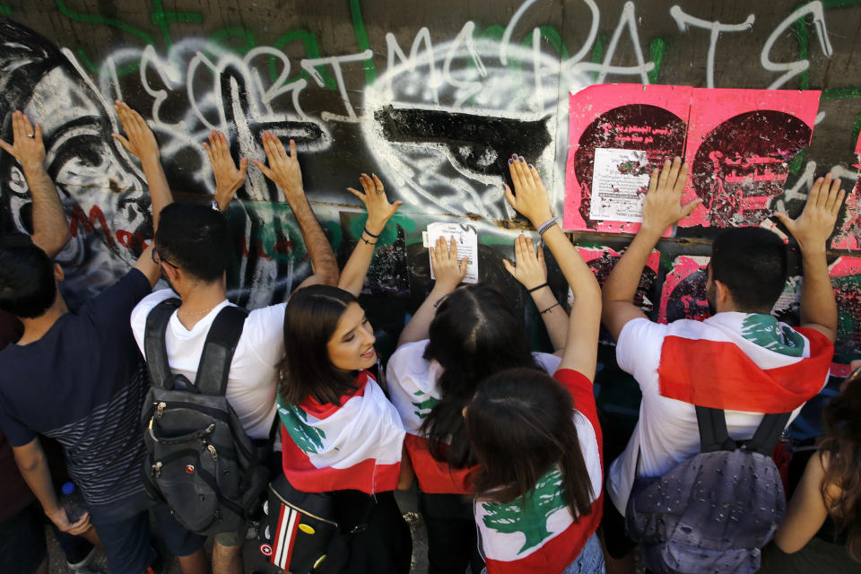 University students chant slogans as they beat their hands against a graffiti-covered wall during ongoing protests against the Lebanese government, in Beirut, Tuesday, Nov. 12, 2019. Protesters resumed demonstrations on Tuesday blocking some roads and governmental institutions. (AP Photo/Bilal Hussein)