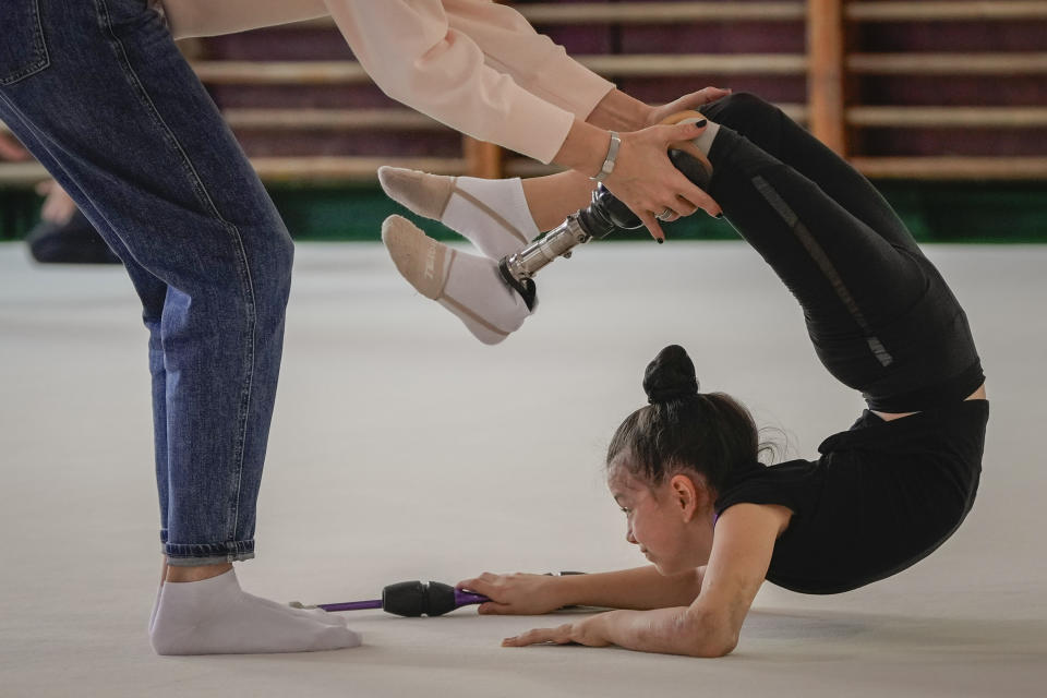 Oleksandra Paskal, an 8-year-old girl with a prosthetic leg, practices rhythmic gymnastics with other girls with coach Inga Kovalchuk in Chornomorsk, Odesa region, Ukraine, Thursday, May 16, 2024. (AP Photo/Efrem Lukatsky)