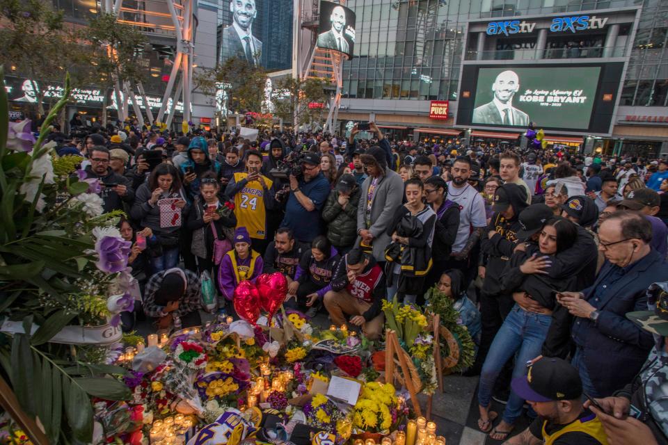 People gather around a makeshift memorial for former NBA and Los Angeles Lakers player Kobe Bryant after learning of his death, at LA Live plaza in front of Staples Center in Los Angeles on January 26, 2020. (Photo by Apu GOMES / AFP)