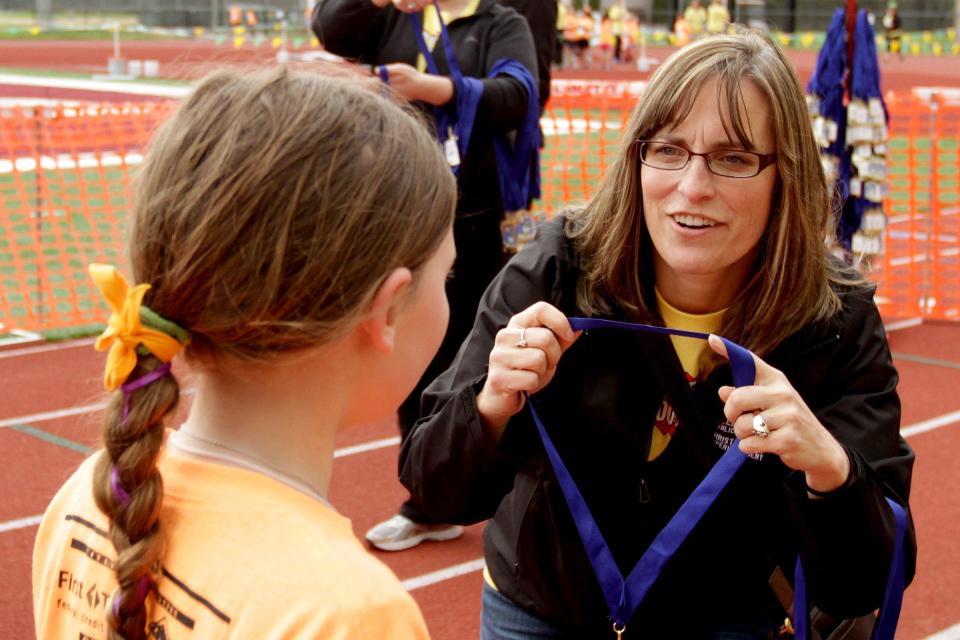 Salem-Keizer Public Schools Superintendent Christy Perry awards a medal to a runner during the 2015 Awesome 3000. Perry has been on the finish line cheering participants every year since she became superintendent.