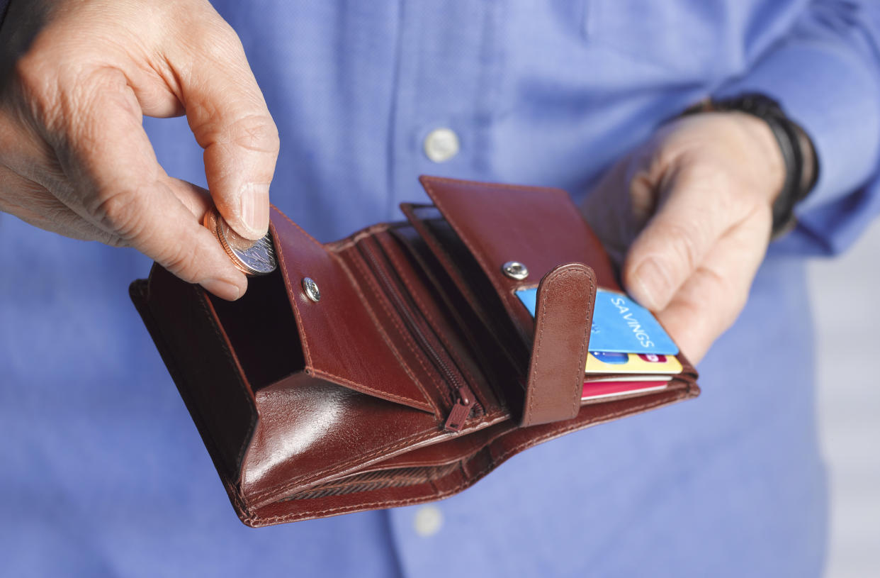 Close up of a man with a wallet putting coins inside