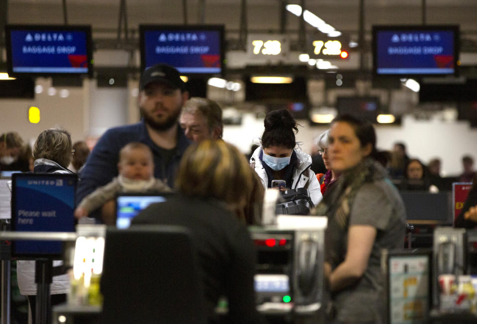 A woman wears a protective mask as she waits to check into a flight to the United States in the main terminal of Brussels International Airport in Brussels, Friday, March 13, 2020. European Union interior ministers on Friday were trying to coordinate their response to the COVID-19 coronavirus as the number of cases spreads throughout the 27-nation bloc and countries take individual measures to slow the disease down. For most people, the new coronavirus causes only mild or moderate symptoms, such as fever and cough. For some, especially older adults and people with existing health problems, it can cause more severe illness, including pneumonia. (AP Photo/Virginia Mayo)