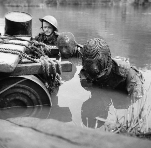 <p>Members of the Doncaster Home Guard swim across a river during an assault exercise in 1942, with two men dressed in camouflage net veils. (Lt. O'Brien/ IWM via Getty Images)</p>