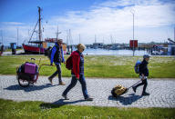 Tourists with backpacks and suitcases arrives at the port of Kloster on the Baltic island Hiddensee in Vitte, Germany, Monday May 25, 2020. In German state Mecklenburg-Western Pomerania, after the travel ban due to the coronavirus protection measures, holidaymakers from other federal states are now allowed to travel to the island. ( Jens Buettner/dpa via AP)