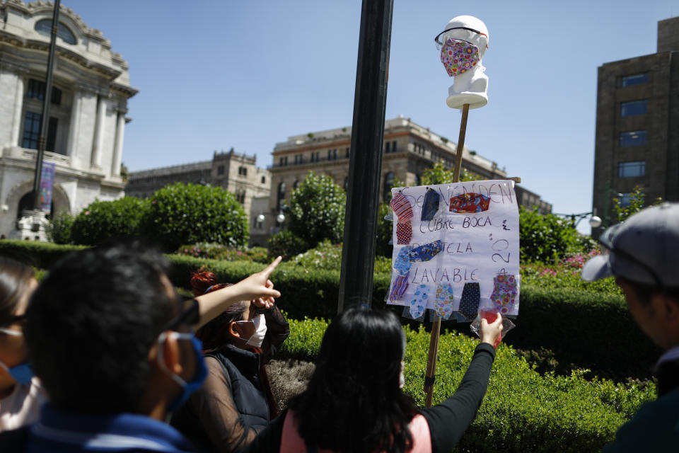 Customers pick out homemade fabric face masks being sold for 20 pesos (around 85 cents) from Jorge Rodriquez, 48, on the street in central Mexico City, Monday, March 23, 2020. Rodriguez was recently laid off from his construction job until further notice, and so he and his wife began making and selling the masks. "You have a family. You have to bring home money," said Rodriguez. "I'm a little afraid, but you have to find a solution for the household costs." Beginning Monday, Mexico's capital shut down museums, bars, gyms, churches, and other non-essential businesses that gather large numbers of people, in an attempt to slow the spread of the new coronavirus.(AP Photo/Rebecca Blackwell)