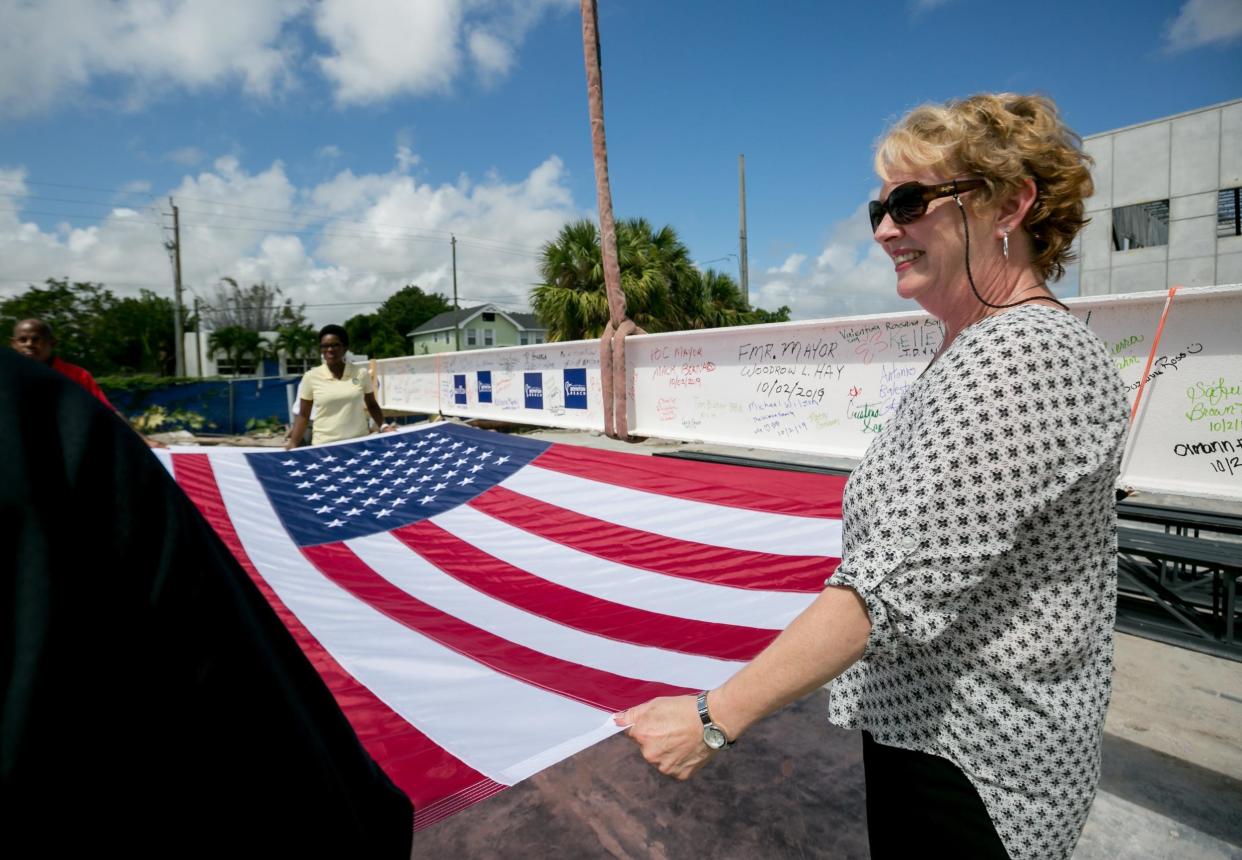 City manager Lori LaVerriere holds a flag during a topping out ceremony with a 1,400 pound, 40 foot long steel beam that will be housed in the City Commission Chambers' ceiling of the new City Hall & Library in Boynton Beach on October 2, 2019.