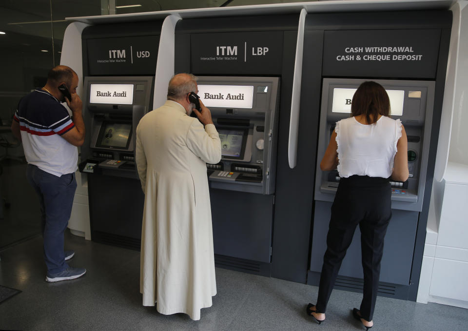 People use an ATM outside a closed bank, in Beirut, Lebanon, Wednesday, Oct. 30, 2019. Lebanese banks have been closed for the last two weeks as the government grapples with mass demonstrations that have paralyzed the country, but an even greater crisis may set in when they reopen Friday. (AP Photo/Hussein Malla)