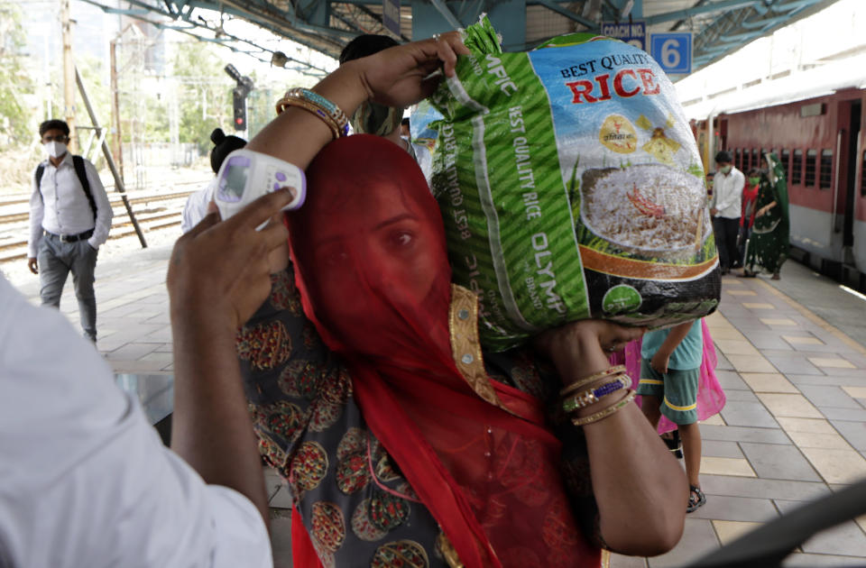 A health worker checks body temperature of a traveler as a precaution against the coronavirus before allowing her to proceed at train station in Mumbai, India, Thursday, May 27, 2021. (AP Photo/Rajanish Kakade)