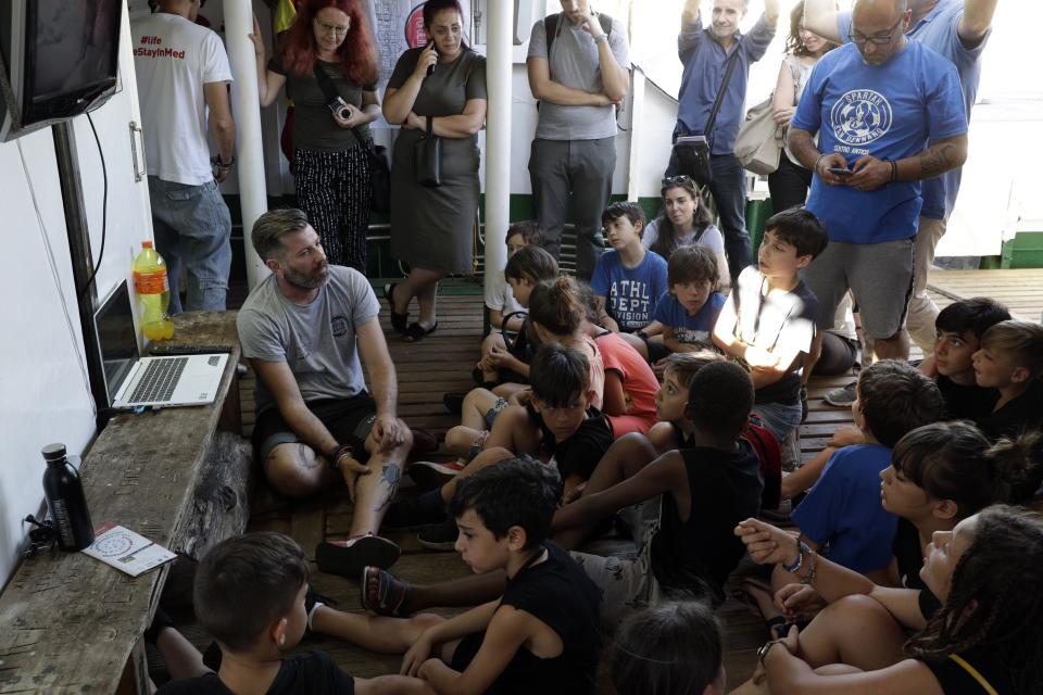 Head of Mission Riccardo Gatti speaks to children aboard the Open Arms ship, moored at the Naples harbor, Italy, Thursday, June 20,2 019. The Spanish NGO migrant ship Open Arms is in Naples with activists speaking to media and the public to mark World Refugee Day. (AP Photo/Andrew Medichini)