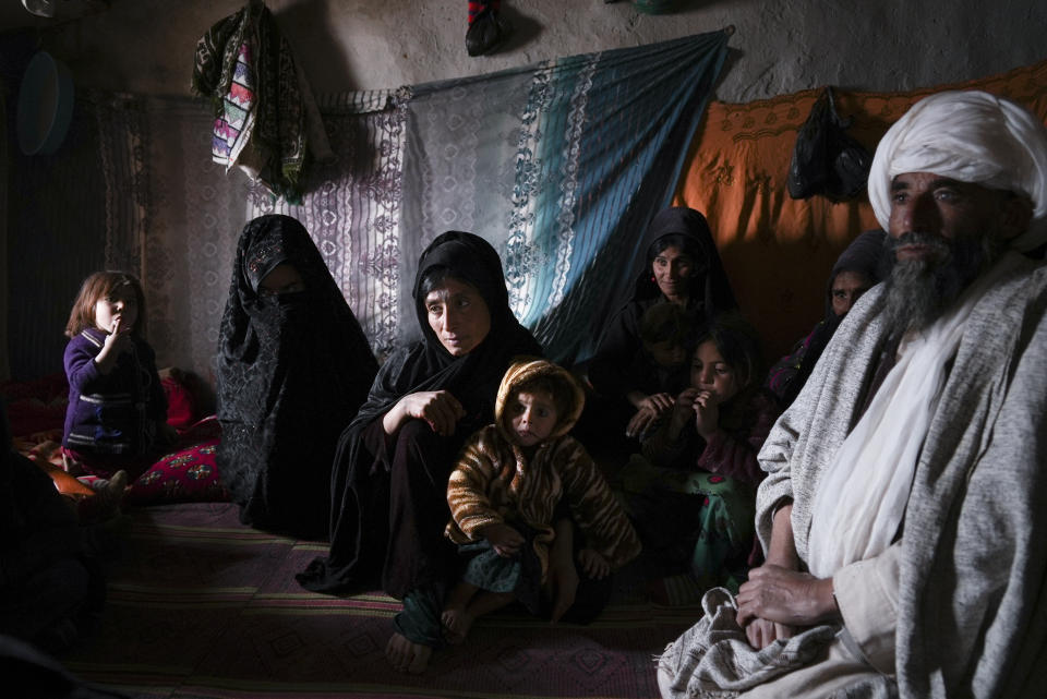 Gul Dasta and her family members gather in their house as they claim to have tried to sell Sallahuddin, one of the boys to get money for food in the IDP camp near Qala-e-Naw, Afghanistan, Tuesday, Dec. 14, 2021. Severe drought now gripping Afghanistan has dramatically worsened the already desperate situation in the country forcing thousands of people to flee their homes and live in extreme poverty. Experts predict climate change is making such events even more severe and frequent. (AP Photo/Mstyslav Chernov)