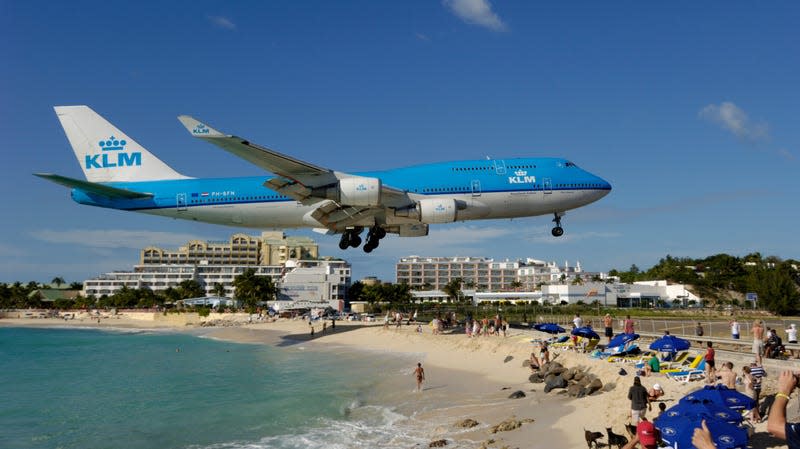 flying low on final-approach landing over Maho Beach with hotels behind B747 on the runway with hills behind. 