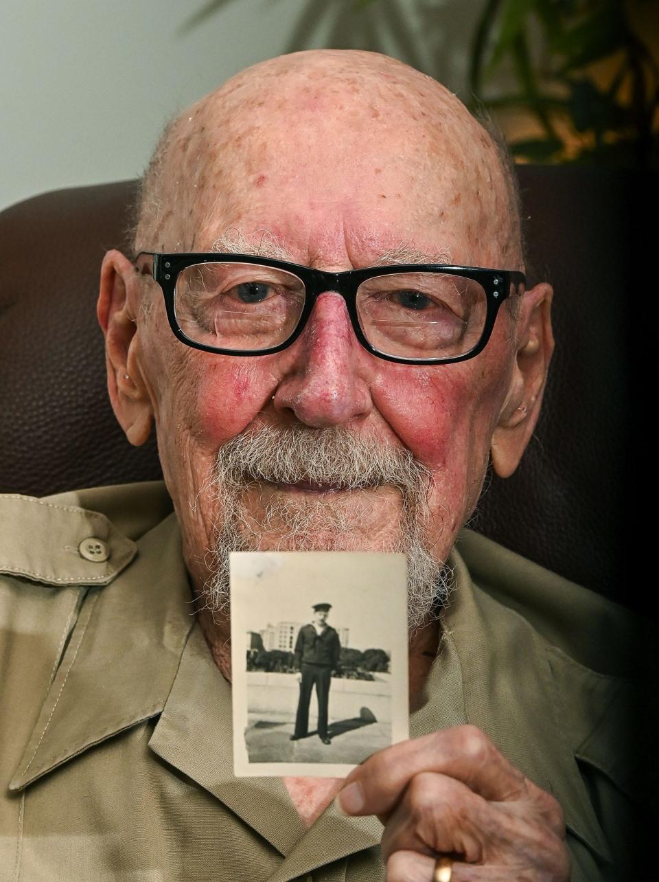 Kenneth Bladen holds a photo of him when he was 19 years old and enlisted in the Navy.