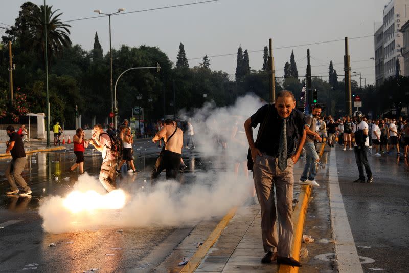 Un hombre reacciona luego de que una granada aturdidora lanzada por la policía explota a su espalda, durante una protesta contra la vacunación obligatoria contra el COVID-19 afuera del edificio del Parlamento en Atenas