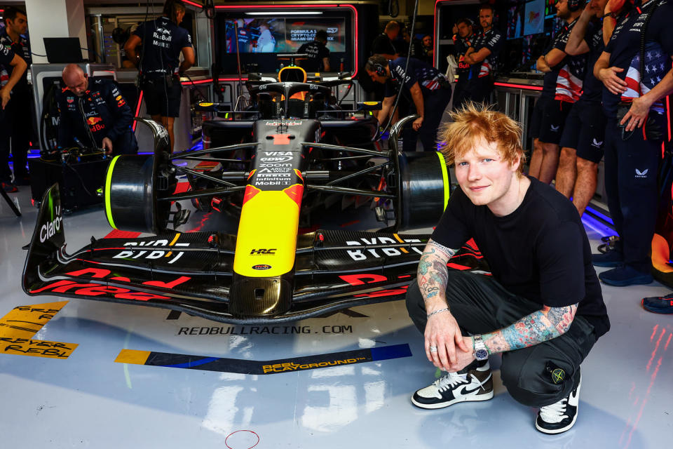 Ed Sheeran squats by a race car for a photo outside the Oracle Red Bull Racing garage (Mark Thompson / Getty Images file)