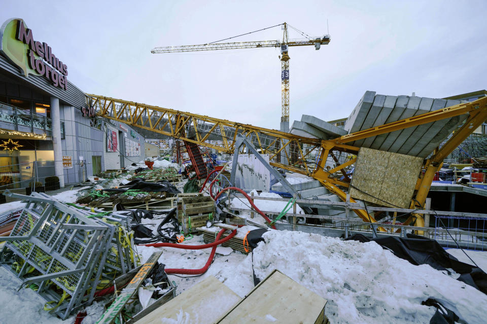 A view of the scene after a construction crane fell over Melhustorget shopping mall, in Melhus, Norway, Friday, Jan. 6, 2023. Strong winds likely have knocked over a construction crane which crashed over a shopping mall in central Norway. Police said one person was unaccounted for and at least one person was slightly injured. (Gorm Kallestad /NTB Scanpix via AP)