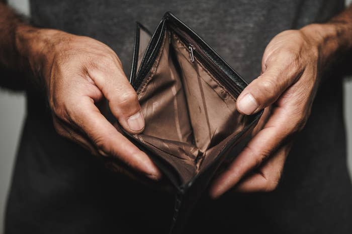 A person holding an open, empty wallet, showcasing the lack of money or contents