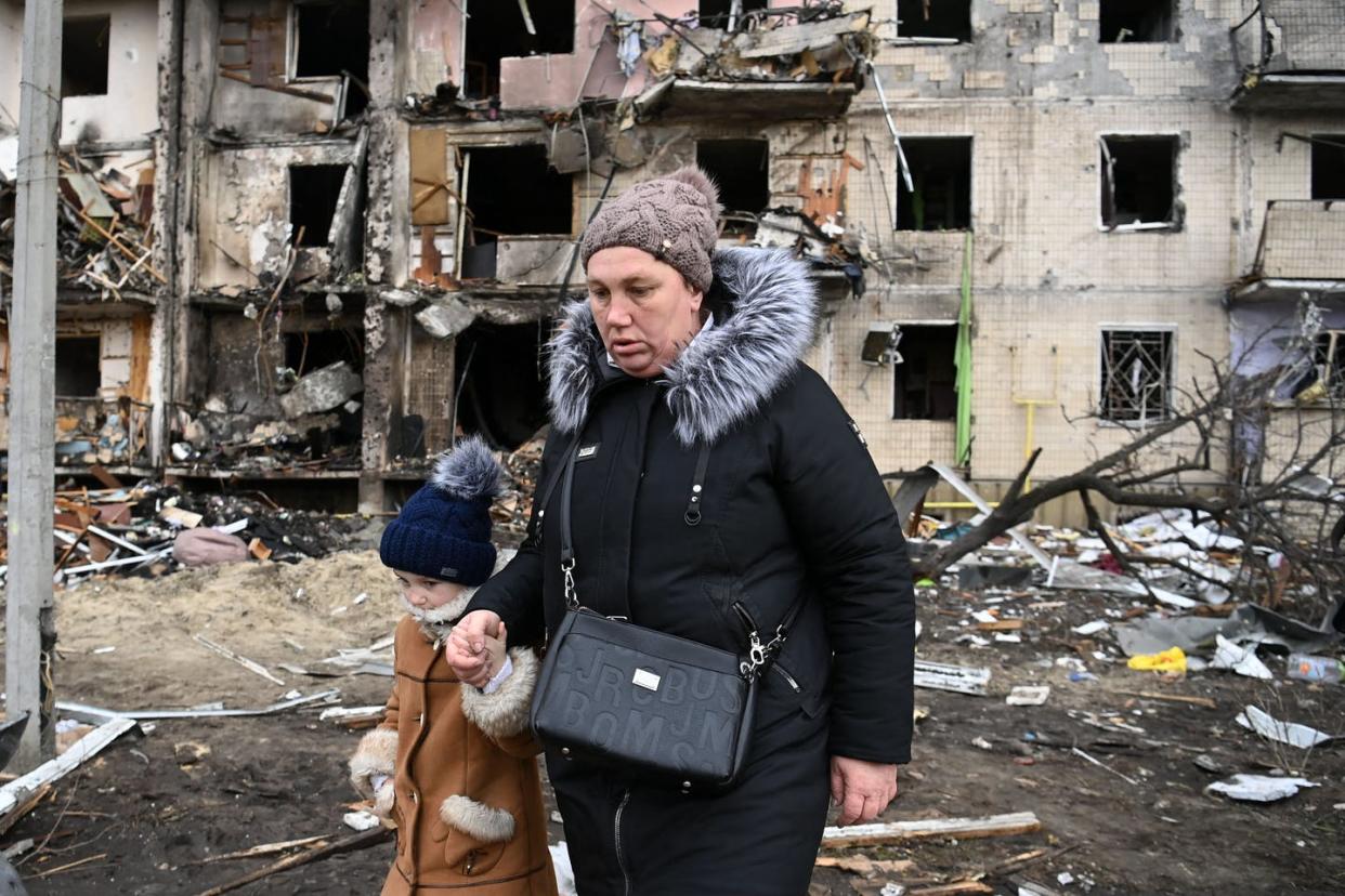 <span class="caption">A woman and child walk away from a damaged residential building in Kyiv, Ukraine, where a military shell allegedly hit on Feb. 25, 2022. </span> <span class="attribution"><a class="link " href="https://media.gettyimages.com/photos/woman-with-a-child-walks-in-front-of-a-damaged-residential-building-picture-id1238745336?s=2048x2048" rel="nofollow noopener" target="_blank" data-ylk="slk:Photo by DANIEL LEAL/AFP via Getty Images;elm:context_link;itc:0;sec:content-canvas">Photo by DANIEL LEAL/AFP via Getty Images</a></span>