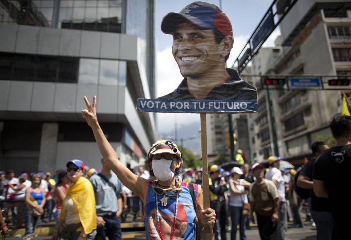 A woman holds up a banner with the image of Venezuelan opposition leader Henrique Capriles as people gather for a demonstration against President Nicolas Maduro in Caracas, Venezuela, Saturday, April 8, 2017. Capriles was banned from running for office for 15 years. Opponents of President Nicolas Maduro are preparing to flood the streets of Caracas on Saturday as part of a week-long protest movement that shows little sign of losing steam. (AP Photo/Ariana Cubillos)