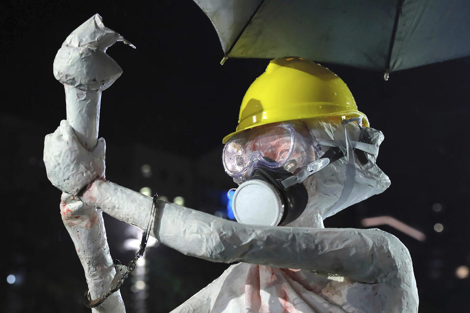 A replica of the Goddess of Democracy statue wearing a hard hat, gas mask, handcuffs and covered in a red liquid is displayed during a demonstration at Victoria Park in Hong Kong, Sunday, Aug. 18, 2019. Protesters turned Hong Kong streets into rivers of umbrellas Sunday as they marched from a packed park and filled a major road in Hong Kong, where mass pro-democracy demonstrations have become a regular weekend activity over the summer. (AP Photo/Kin Cheung)