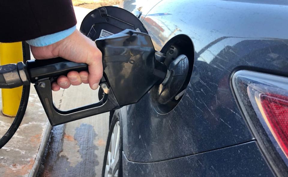 A driver fills car at gas station. Medium closeup. 