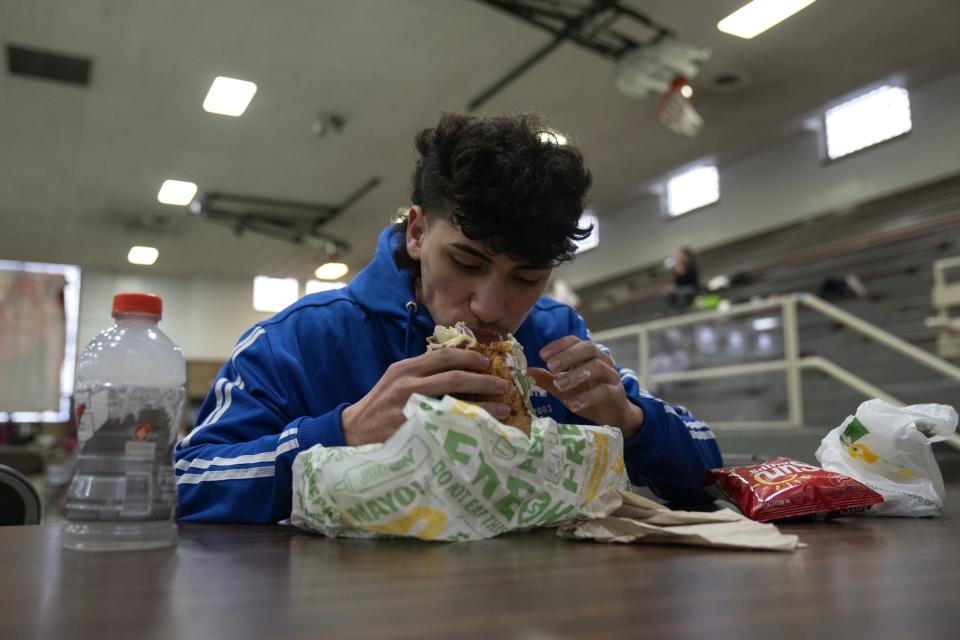 Julian David Lugo, 19, who fights at the 139-pound weight class, eats his dinner after making weight on a night of quarter-final boxing matches at the Chicago Golden Gloves tournament Thursday, March 16, 2023, at Cicero Stadium in Cicero, Ill. Lugo trains out of the Rockford Patriots Boxing Club in Rockford, Ill. (AP Photo/Erin Hooley)