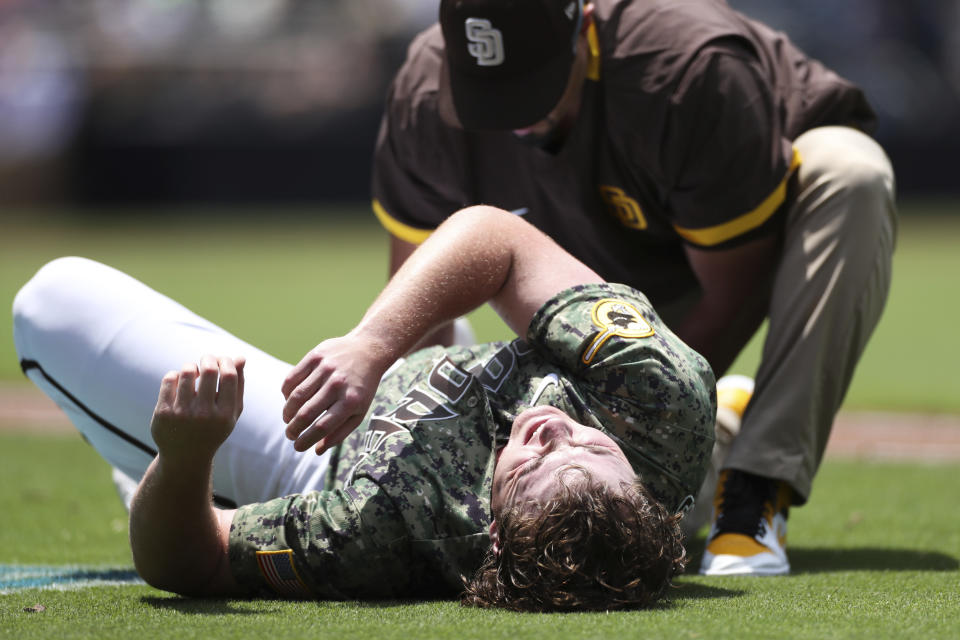 San Diego Padres starting pitcher Ryan Weathers is checked by a trainer after a collision with Colorado Rockies' Jon Gray in the third inning of a baseball game Sunday, July 11, 2021, in San Diego. (AP Photo/Derrick Tuskan)