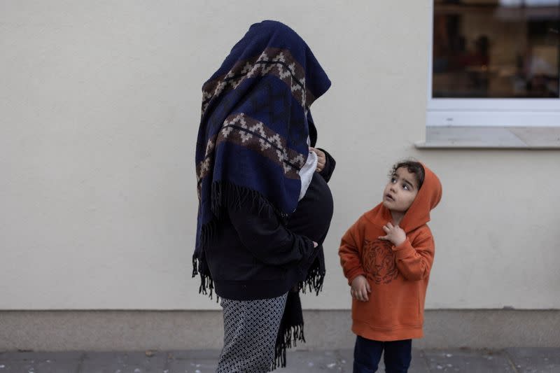Pregnant Iraqi migrant woman stands with her daughter at the migrants centre in Bialystok