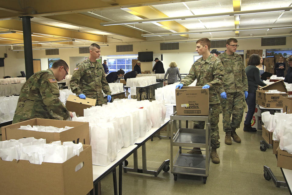 Members of the West Virginia National Guard and many volunteers assist with the preparation and distribution of around 2000 school lunches in the cafeteria at Greenbrier East High School in Fairlea, WV., Monday, March 23, 2020. The Greater Greenbrier Long-Term Recovery Committee and the National Guard partnered with Greenbrier County Schools to help feed breakfast and lunch to students during the school shutdown due to coronavirus.(Jenny Harnish/The Register-Herald via AP)