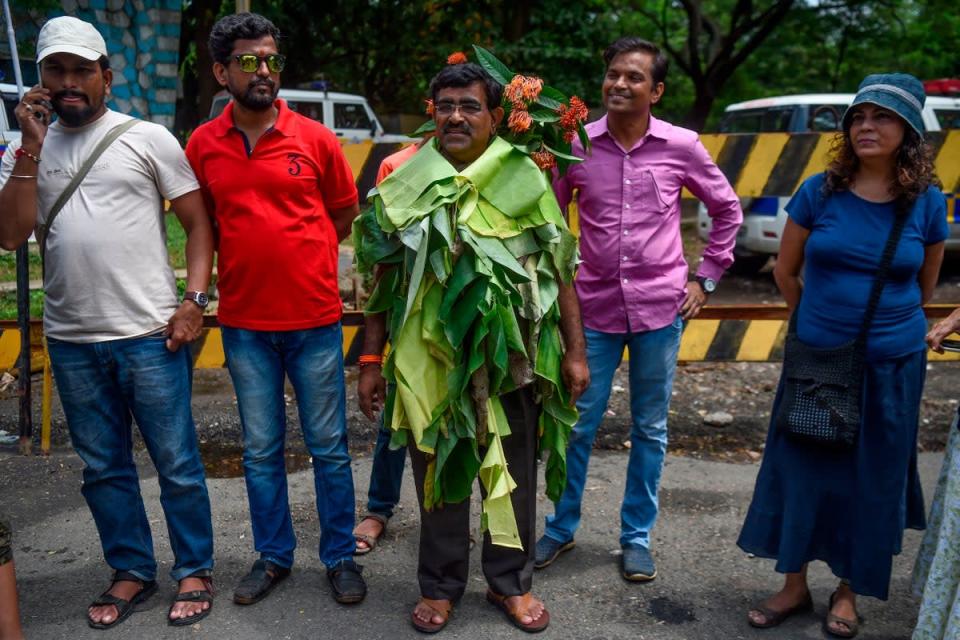 Activist Dadarao Bilhore (centre) stands wearing a dress made from banana leaves and flowers found in the Aarey forest as he protests against the destruction of Aarey forest (Getty)