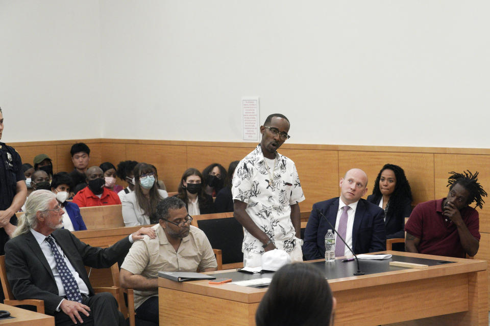 Vincent Ellerbe, center, address the court speaking for himself and Thomas Malik, second from left, and James Irons, far right, during a hearing for their exoneration at Brooklyn Supreme Court, Friday, July 15, 2022, in New York. After decades in prison, Ellerbe, Malik and Irons were cleared in one of the most horrifying crimes of New York’s violent 1990s, the killing of a clerk who was set on fire in a subway toll booth. (AP Photo/Bebeto Matthews)
