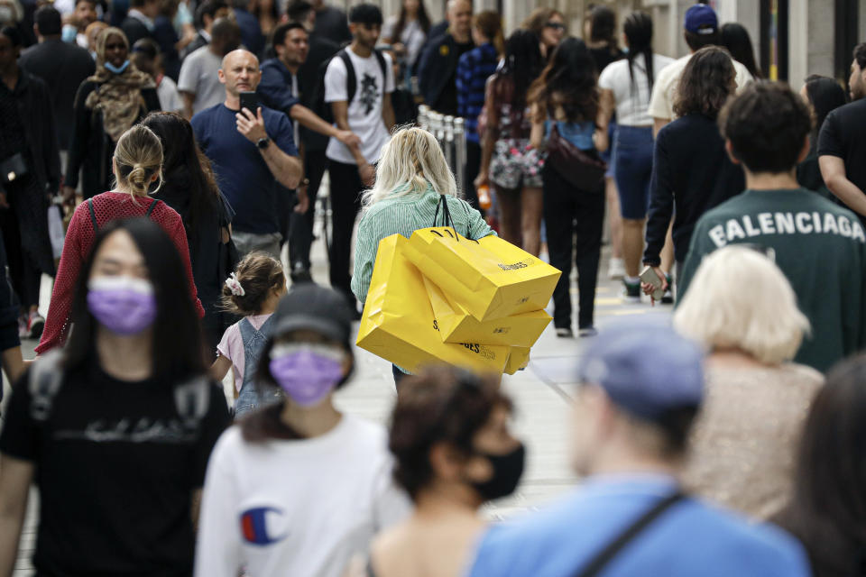 People walk with bags after shopping at the Selfridges department store in London, Monday, June 15, 2020