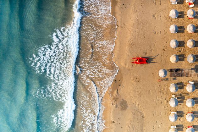 Aerial view of crashing waves on empty beach with white parasols, Vieste, Foggia province, Gargano, Apulia, Italy (Photo: Roberto Moiola / Sysaworld via Getty Images)