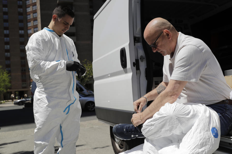 Environmental Specialist Anthony Olivieri, left, and Safety Director Tony Barzelatto put on protective gear before disinfecting a floor and common areas in a Co-op City building in the Bronx borough of New York, Wednesday, May 13, 2020. Regular cleanings occur throughout the common areas of the buildings while the heavy disinfecting occurs in response to specific incidents, in this case reports of two coronavirus cases on the same floor. (AP Photo/Seth Wenig)