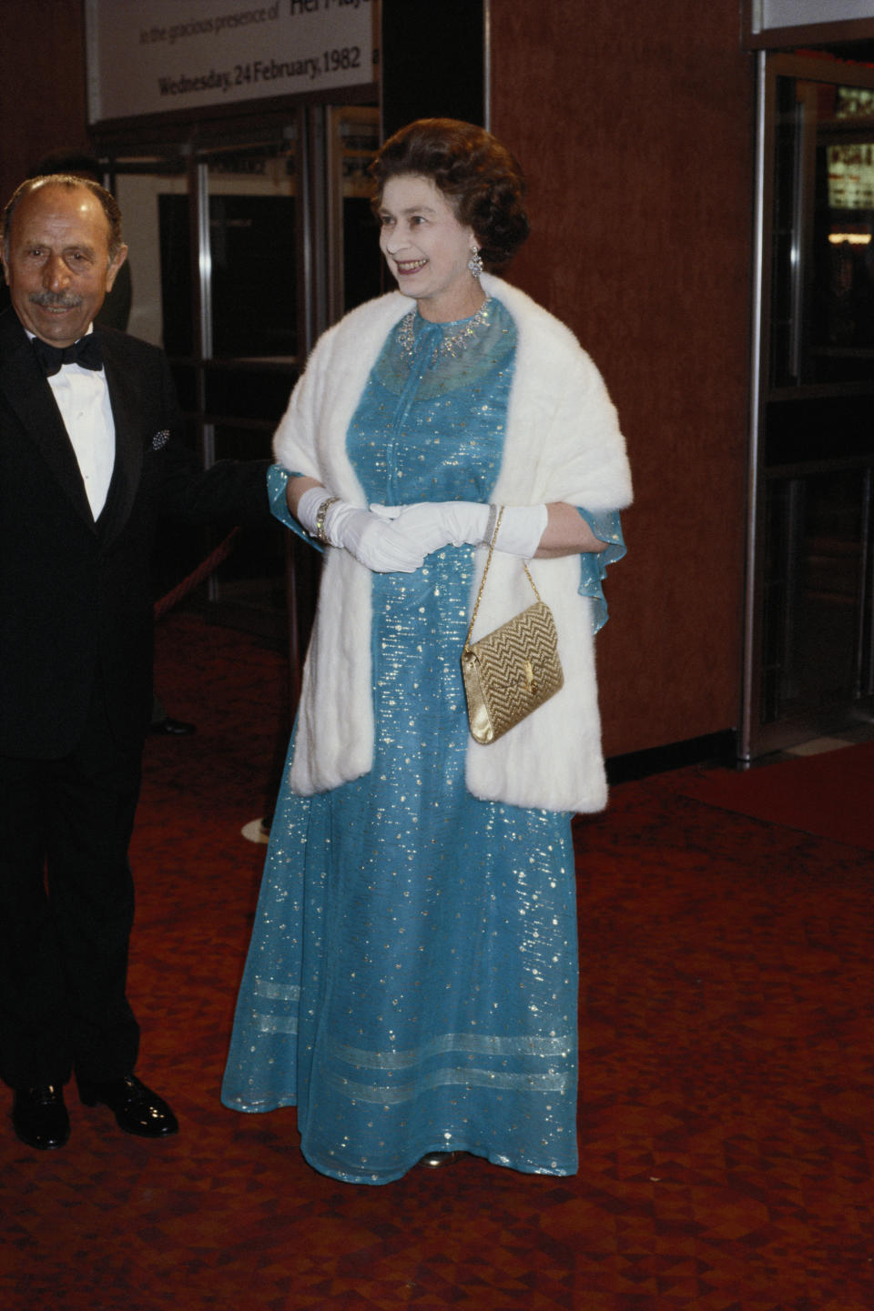 <p>Her Majesty wore a royal blue gown and white shawl for the red carpet back in 1982. (Getty Images)</p> 