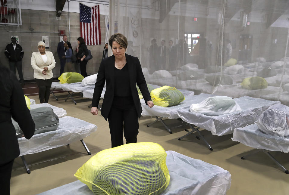 Massachusetts Governor Maura Healey pauses to look at the Army cots set up on the gym floor as State and local officials toured the Melnea A. Cass Recreational Complex Wednesday, Jan. 31, 2024, in the Roxbury neighborhood of Boston. The facility will house over 300 migrants. (John Tlumacki/The Boston Globe via AP, Pool)