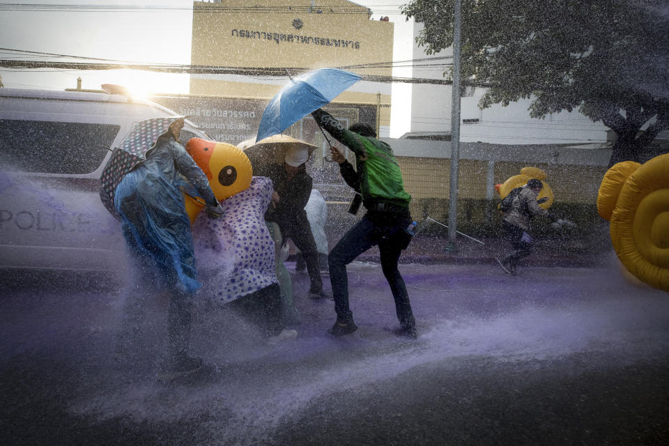 Pro-democracy protesters take cover with inflatable ducks and umbrellas as police fire water cannons during an anti-government rally near the Parliament in Bangkok, Tuesday, Nov. 17, 2020. Thailand's political battleground shifted to the country's Parliament Tuesday, where lawmakers are considering proposals to amend the country's constitution, one of the core demands of the student-led pro-democracy movement. (AP Photo/Wason Wanichakorn)