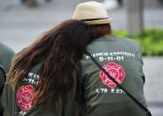 Two people with shirts commemorating New York City Fire Department firefighter Frankie Esposito sit at the South reflecting pool at the 9/11 Memorial during ceremonies marking the 12th anniversary of the 9/11 attacks on the World Trade Center in New York, September 11, 2013. (REUTERS/Stan Honda)