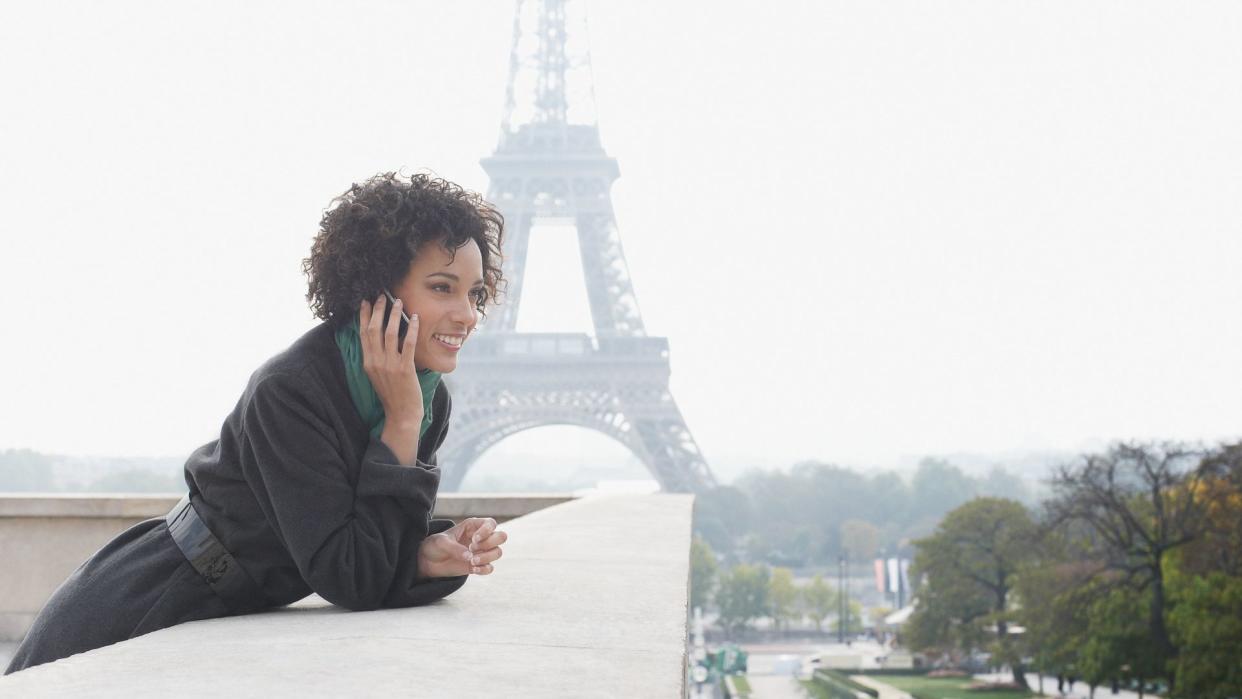 Woman outdoors on her mobile phone by the Eiffel Tower.