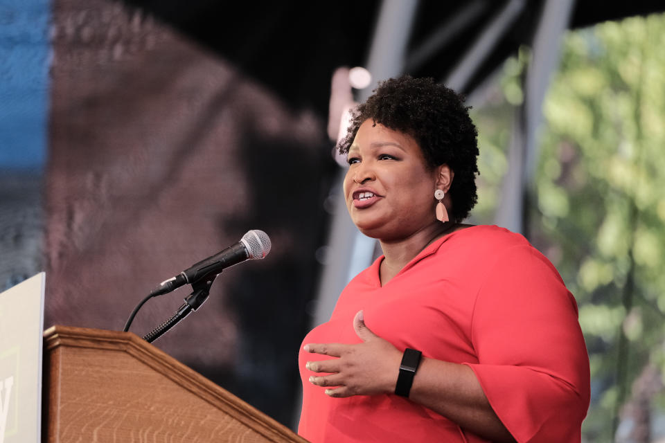 Stacey Abrams stands at podium with a microphone.