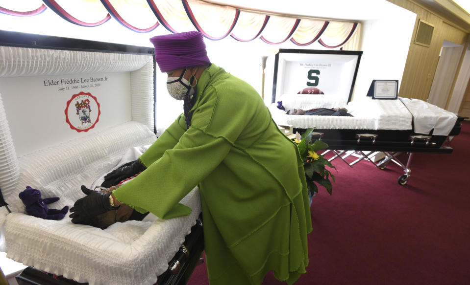 Sandy Brown touches the forehead of her late husband, Freddie Lee Brown, Jr., after she cries over her late son, Freddie Lee Brown, III, right, Friday, April 10, 2020 at the Dodds-Dumanois Funeral Home and Cremation Center in Flint, Mich. Sandy Brown of Grand Blanc lost her 59-year-old husband, Freddie Lee Brown Jr., and her 20-year-old son, Freddie Lee Brown III, to the new coronavirus within days of each other. (Todd McInturf/Detroit News via AP)