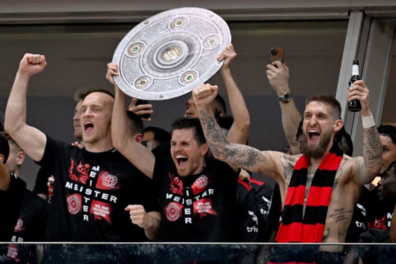 Leverkusen players cheers with a stylized championship trophy from the stands into the stadium to the fans who stormed the pitch following the German Bundesliga soccer match between Bayer 04 Leverkusen and SV Werder Bremen at BayArena. Federico Gambarini/dpa