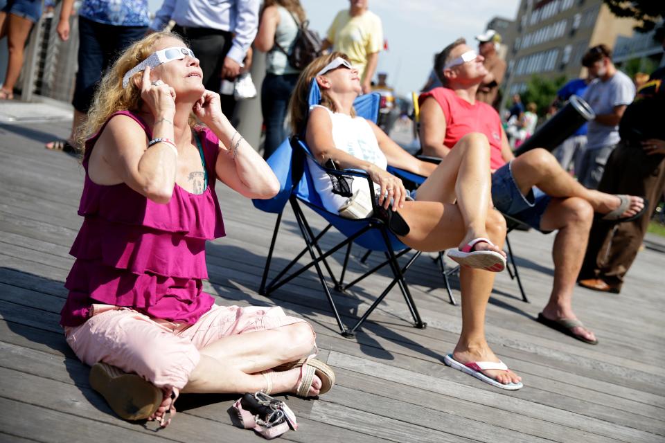 Betty Tumbleson of Green Bay sits on the CityDeck while looking at the solar eclipse with special glasses on Aug. 21, 2017, during a viewing party hosted by the city of Green Bay and Downtown Green Bay Inc.