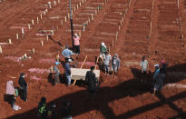 Workers prepare a coffin for burial at the special section of Jombang Public Cemetery reserved for those who died of COVID-19, in Tangerang, on the outskirts of Jakarta, Indonesia, Wednesday, Aug. 4, 2021. Indonesia surpassed 100,000 confirmed COVID-19 deaths on Wednesday, a grim milestone in a country struggling with its worst pandemic wave fueled by the delta variant, amid concerns the actual figure could be much higher. (AP Photo/Tatan Syuflana)