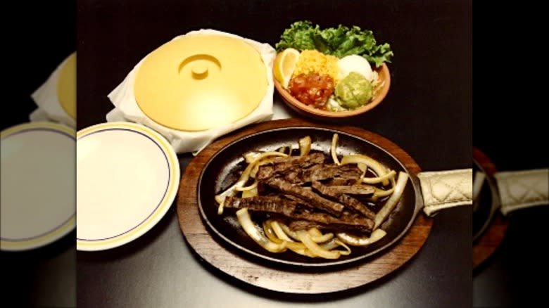 a table with a skillet of fajitas