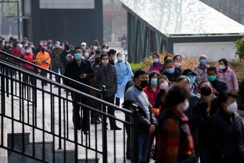 People wearing face masks line up to enter a supermarket in Wuhan