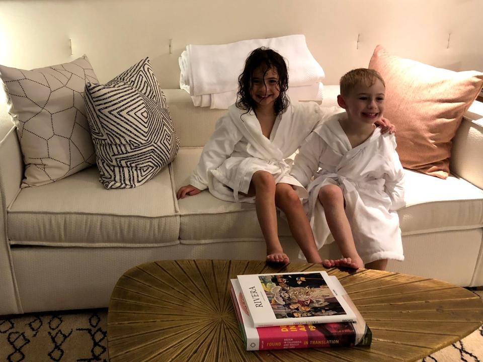 Two kids smiling in robes in a hotel room