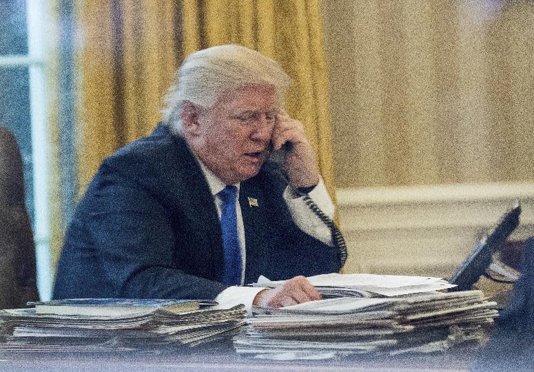 President Donald Trump speaks on the phone with German Chancellor Angela Merkel, Saturday, Jan. 28, 2017, in the Oval Office at the White House in Washington. (AP Photo/Andrew Harnik)