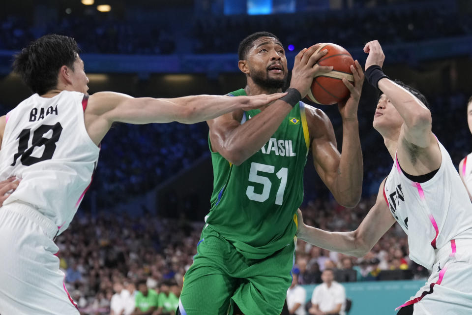 El brasileño Bruno Caboclo se abre espacio entre los japoneses Yudai Baba (izquierda) y Yuta Watanabe en el torneo de baloncesto de los Juegos Olímpicos de París, el viernes 2 de agosto de 2024, en Villeneuve-d'Ascq, Francia. (AP Foto/Mark J. Terrill)